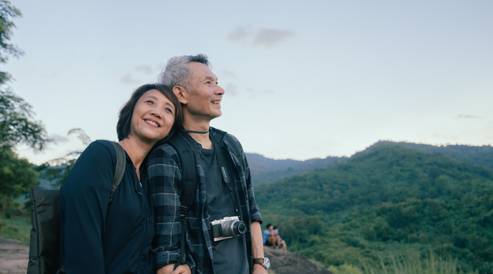 Older couple smiling at the top of a mountain.