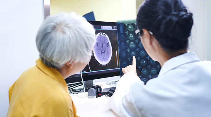 Doctor and older adult looking at a brain scan.