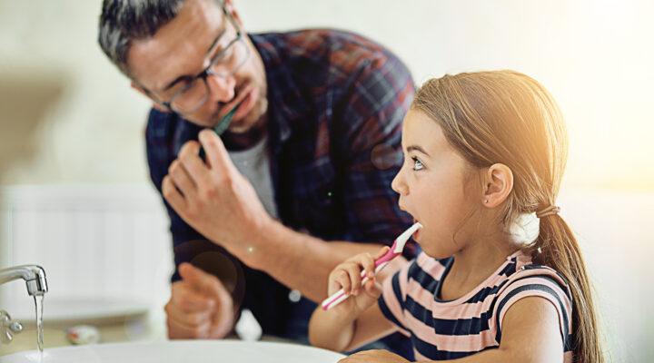 Dad teaching daughter to brush