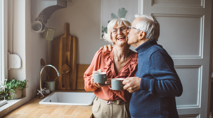 Older couple smiling and drinking coffee.