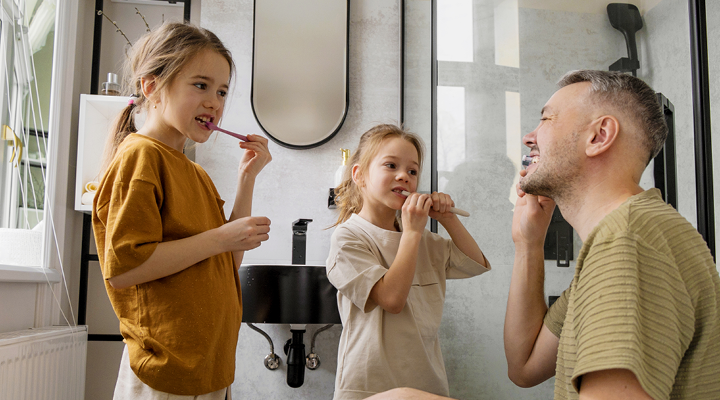Father and daughter brushing their teeth together.