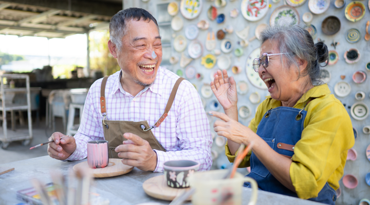 Adult couple smiling, laughing and painting.