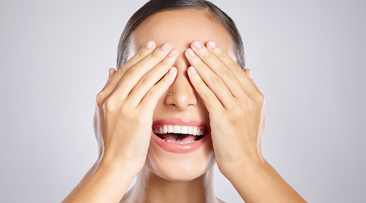 Girl covering her eyes and smiling.