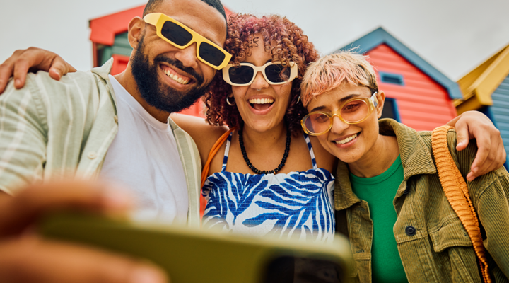 Friends smiling and taking a selfie with sunglasses on.