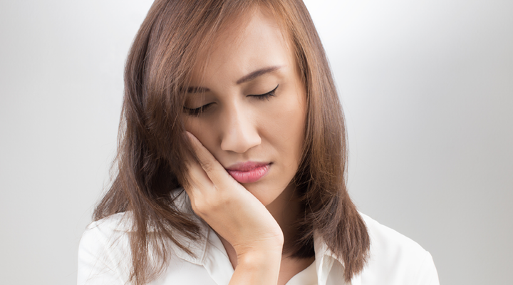 Person holding their mouth and jaw in pain.