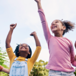 Group of children smiling and dancing outside.