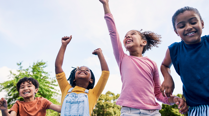 Group of children smiling and dancing outside.