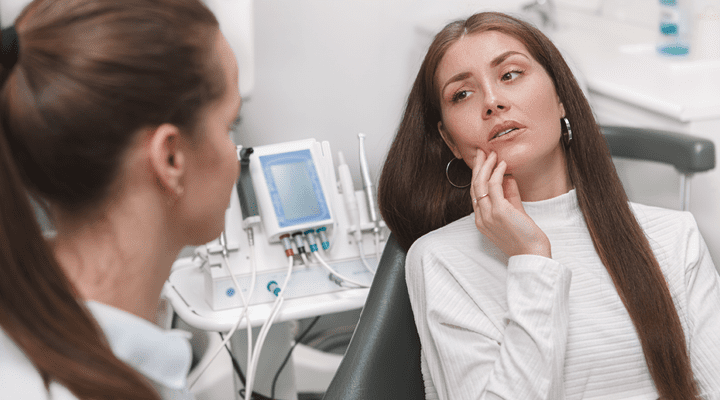 Person holding their jaw in pain at the dentist.