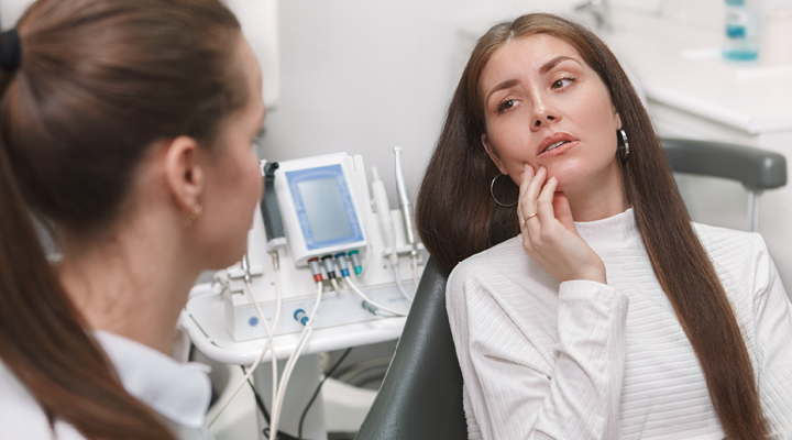 Person holding their jaw in pain at the dentist.
