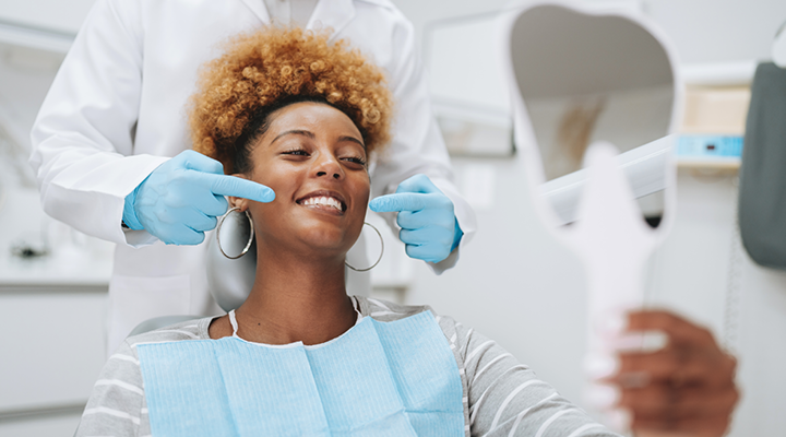 Patient smiling and getting their teeth cleaned at the dentist.