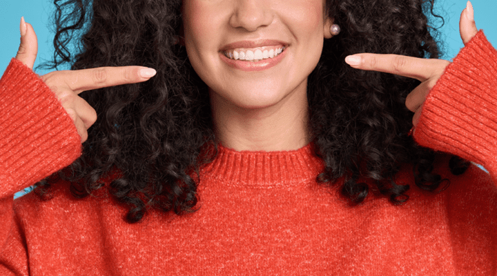 Person pointing at their smile.