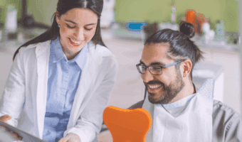 Person smiling in the dental chair, talking to a dentist.