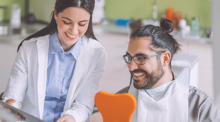 Person smiling in the dental chair, talking to a dentist.