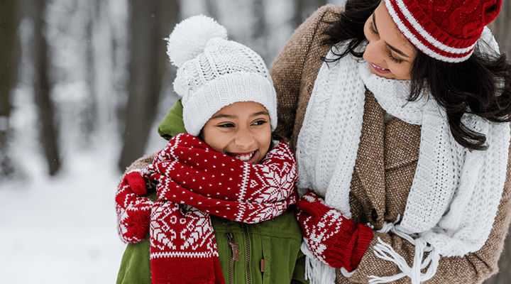 Mother and daughter smiling outside in the snow.