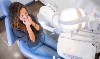 Person covering their mouth in the dental chair.